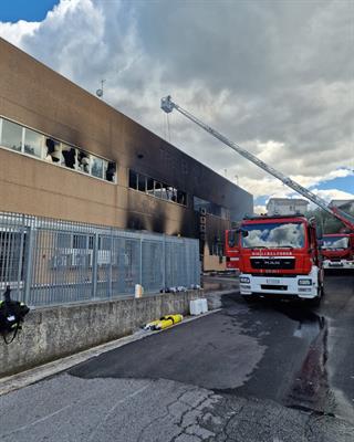 Autoscala impegnato nelle operazioni di spegnimento tra i resti dello stabilimento